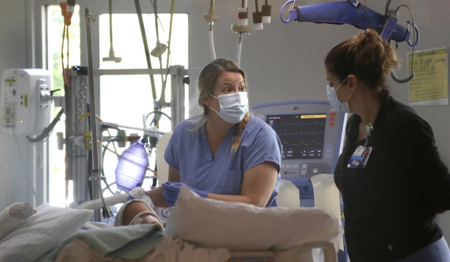 FILE - In this May 8, 2020, file photo, registered nurse Katie Hammond, left, works with another nurse on a patient in the COVID-19 Intensive Care Unit at Harborview Medical Center , in Seattle. The number of deaths in Washington because of the coronavirus has reached 1,000, the Washington State Department of Health reported Saturday, May 16, 2020. The agency added eight more deaths and listed the total number of confirmed cases at 18,288. (AP Photo/Elaine Thompson, File) **FILE**