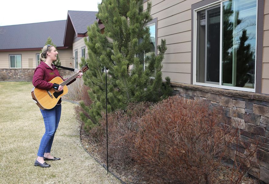 In this April 17, 2020, photo, Kirsten Wells plays guitar for residents of Rising Mountains Assisted Living in Bigfork, Mont. She played songs like "Take Me Out to the Ball Game," "When It's Springtime in the Rockies" and "King of the Road." (Mackenzie Reiss/The Daily Inter Lake via AP)