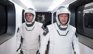 In this Jan. 17, 2020 photo made available by SpaceX, NASA astronauts Bob Behnken, left, and Doug Hurley, wearing SpaceX spacesuits, walk through the Crew Access Arm connecting the launch tower to the SpaceX Crew Dragon spacecraft during a dress rehearsal at NASA&#39;s Kennedy Space Center in Cape Canaveral, Fla. For their May 27, 2020 mission, Hurley will be in charge of launch and landing and Behnken will oversee rendezvous and docking at the International Space Station. (SpaceX via AP)