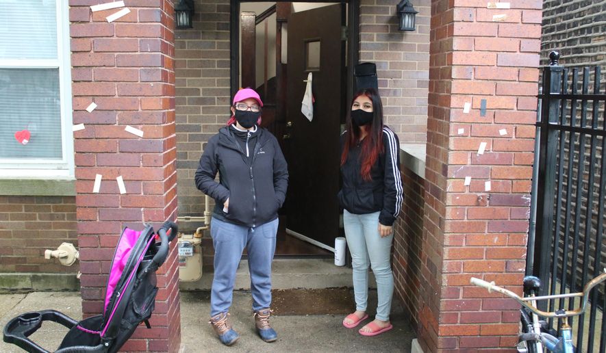 In this May 14, 2020 photo, Erendira Martinez and her daughter stand outside their home in the Little Village neighborhood of Chicago. Chicago’s Little Village neighborhood is known as the heart of Mexican culture in the city. It’s also located in the zip code area with one of the highest rates of positive coronavirus cases in the city. Both Martinez and her daughter, along with Martinez' husband, tested positive for COVID-19. All have since recovered. (AP Photo/Noreen Nasir)