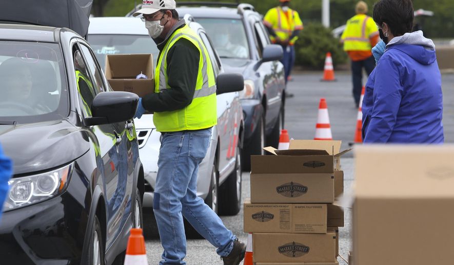 In this Wednesday May 20, 2020 photo, Food Bank of Delaware, DelDOT, the Delaware Army National Guard and scores of volunteers come together to serve as many as many as 2,500 families in the Food Bank's Drive-Thru Mobile Pantry at Dover International Speedway in Dover, Del. William Bretzger/The News Journal via AP)