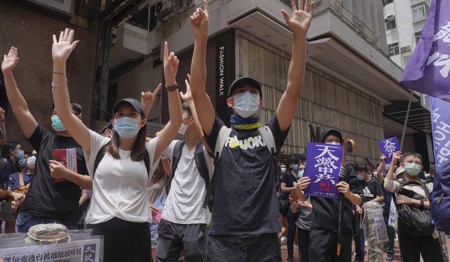 Protesters gesture with five fingers, signifying the "Five demands - not one less" as they march along a downtown street during a pro-democracy protest against Beijing's national security legislation in Hong Kong, Sunday, May 24, 2020. Hong Kong's pro-democracy camp has sharply criticised China's move to enact national security legislation in the semi-autonomous territory. They say it goes against the "one country, two systems" framework that promises the city freedoms not found on the mainland. (AP Photo/Vincent Yu)