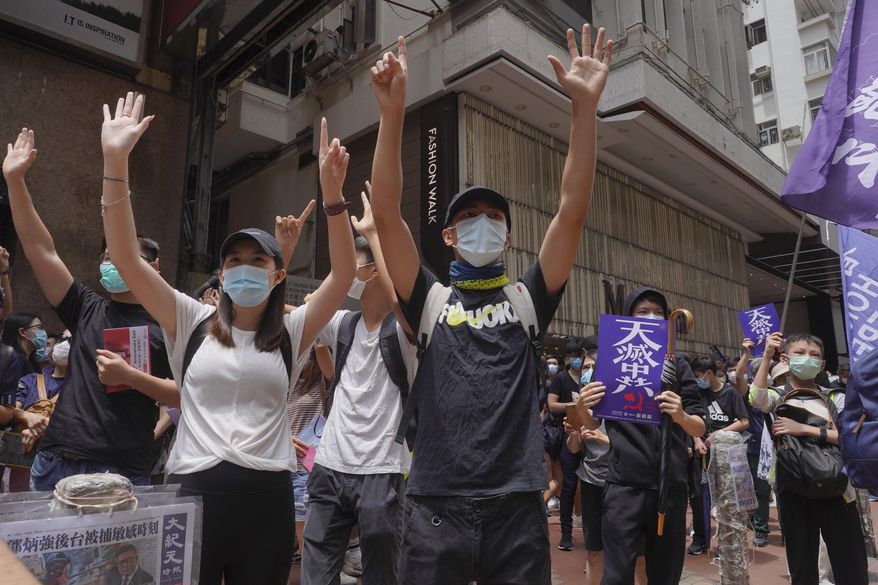 Protesters gesture with five fingers, signifying the "Five demands - not one less" as they march along a downtown street during a pro-democracy protest against Beijing's national security legislation in Hong Kong, Sunday, May 24, 2020. Hong Kong's pro-democracy camp has sharply criticised China's move to enact national security legislation in the semi-autonomous territory. They say it goes against the "one country, two systems" framework that promises the city freedoms not found on the mainland. (AP Photo/Vincent Yu)