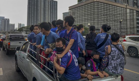Migrant construction workers, some wearing face masks, travel in the back of a crew cab in Bangkok, Thailand, Monday, May 25, 2020. Thai government continue to ease restrictions related to running business in capital Bangkok that were imposed weeks ago to combat the spread of COVID-19. (AP Photo/Gemunu Amarasinghe)