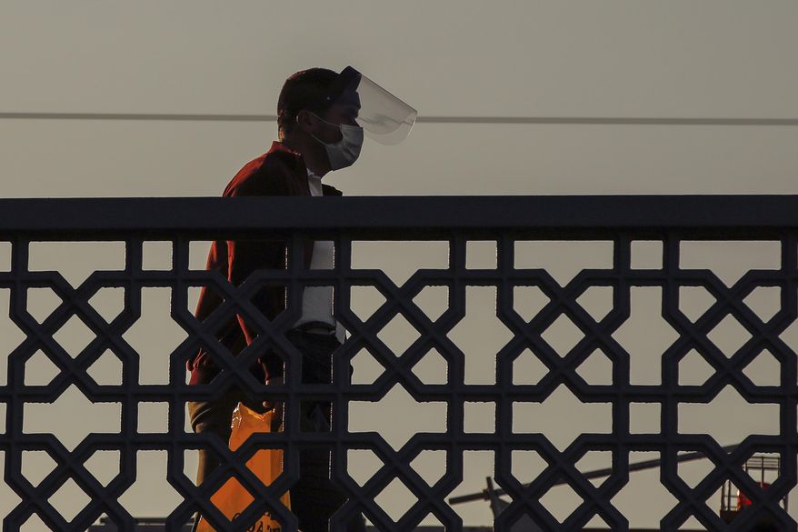 A man walks nearby the historical Suleymaniye Mosque where only few face masked people allowed to offer the Eid al-Fitr prayer amid concerns of the coronavirus outbreak, in Istanbul, early Sunday, May 24, 2020. Muslims in the world are marking a muted and gloomy religious festival of Eid al-Fitr, the end of the fasting month of Ramadan _ a usually joyous three-day celebration that has been significantly toned down due to the new coronavirus outbreak. (AP Photo/Emrah Gurel)
