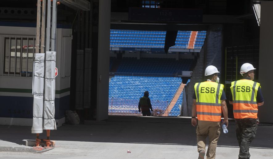 Workers walk into Real Madrid&#39;s Santiago Bernabeu stadium in Madrid, Spain, Monday, May 25, 2020. Spanish league clubs are now allowed to train with groups of up to 14 players as the league stays on track to restart in less than three weeks. (AP Photo/Paul White)