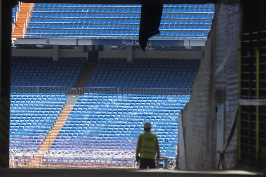 Workers walk into Real Madrid's Santiago Bernabeu stadium in Madrid, Spain, Monday, May 25, 2020. Spanish league clubs are now allowed to train with groups of up to 14 players as the league stays on track to restart in less than three weeks. (AP Photo/Paul White)