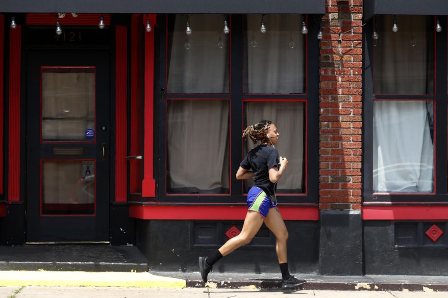 In this Thursday, May 7, 2020, file photo, a person jogs past a closed nightclub in St. Louis. Running is seeing an increase in participation since the coronavirus outbreak began taking off in the United States. (AP Photo/Jeff Roberson, File) **FILE**