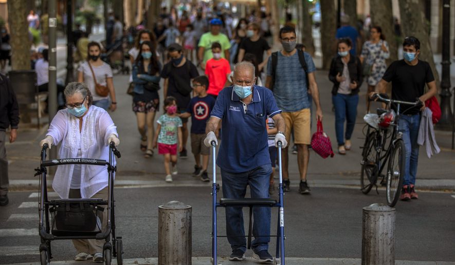 People walk on a street in Barcelona on Monday, May 25, 2020. Roughly half of the population, including residents in the biggest cities of Madrid and Barcelona, are entering phase 1 on Monday, which allows social gatherings in limited numbers, restaurant and bar service with outdoor sitting and some cultural and sports activities. (AP Photo/Emilio Morenatti)