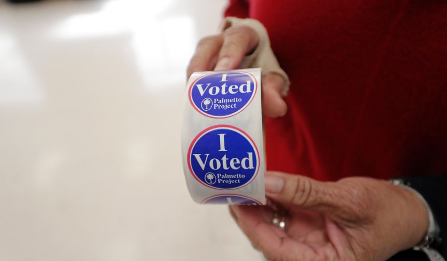 Polling manager Diana Belton shows a roll of voting stickers as people arrive to vote in the Democratic presidential primary in Hopkins, S.C., Saturday, Feb. 29, 2020. (AP Photo/Gerald Herbert)
