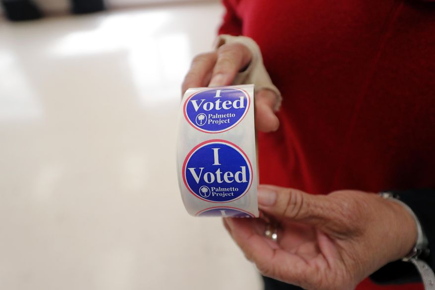 Polling manager Diana Belton shows a roll of voting stickers as people arrive to vote in the Democratic presidential primary in Hopkins, S.C., Saturday, Feb. 29, 2020. (AP Photo/Gerald Herbert)