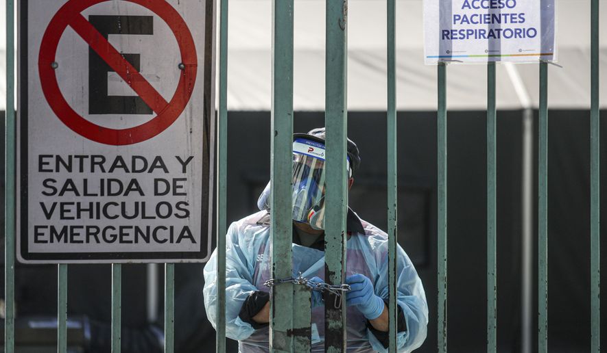 A health worker opens the gate leading to the field clinic where patients suspected of having the new coronavirus are treated at San Jose Hospital in Santiago, Chile, Friday, May 15, 2020. (AP Photo/Esteban Felix)