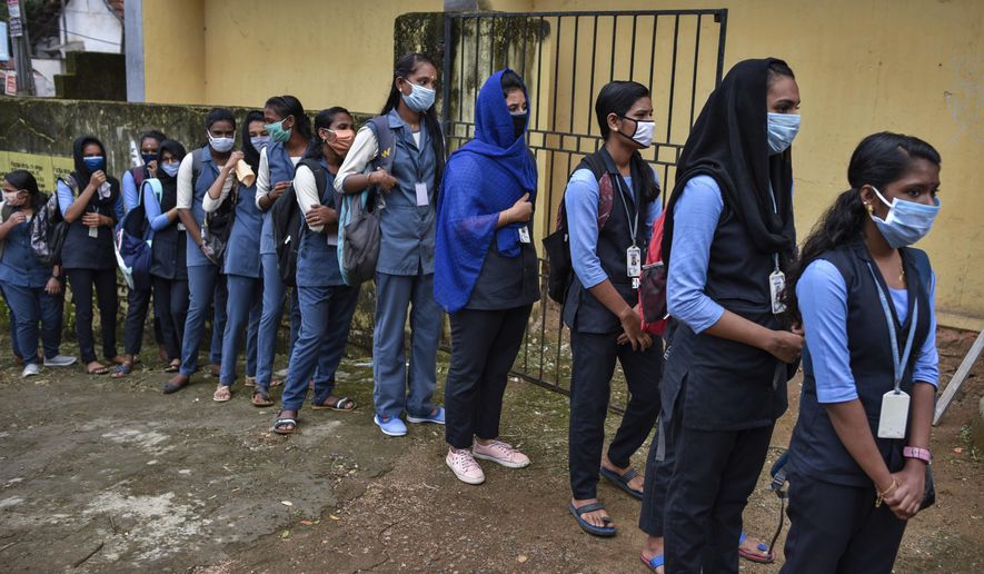 School children wearing masks line up to get their hands sanitized and temperatures checked as they arrive to appear for state board examination during the coronavirus pandemic in Kochi, Kerala state, India, Tuesday, May 26, 2020. (AP Photo/R S Iyer)