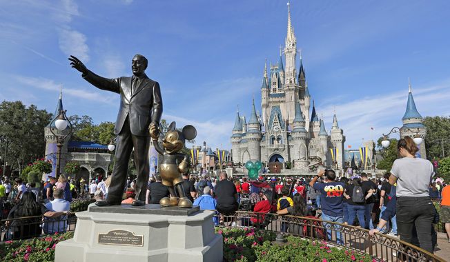 In this Jan. 9, 2019 photo, guests watch a show near a statue of Walt Disney and Micky Mouse in front of the Cinderella Castle at the Magic Kingdom at Walt Disney World in Lake Buena Vista, part of the Orlando area in Fla. Officials from SeaWorld and Disney World say they hope to open their theme parks in Orlando, Fla., in June and July. A city task force approved the plans on Wednesday, May 27, 2020. (AP Photo/John Raoux, File)  **FILE**
