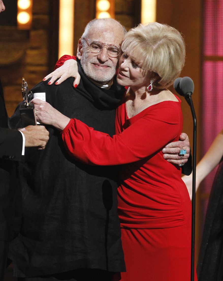 FILE -This June 12, 2011 file photo shows Larry Kramer, left, and Daryl Roth embracing after they won the Tony Award for Best Revival of a Play for "The Normal Heart" during the 65th annual Tony Awards in New York. Kramer, the playwright whose angry voice and pen raised theatergoers’ consciousness about AIDS and roused thousands to militant protests in the early years of the epidemic, died Wednesday, May 27, 2020 in Manhattan of pneumonia. He was 84. (AP Photo/Jeff Christensen, File)