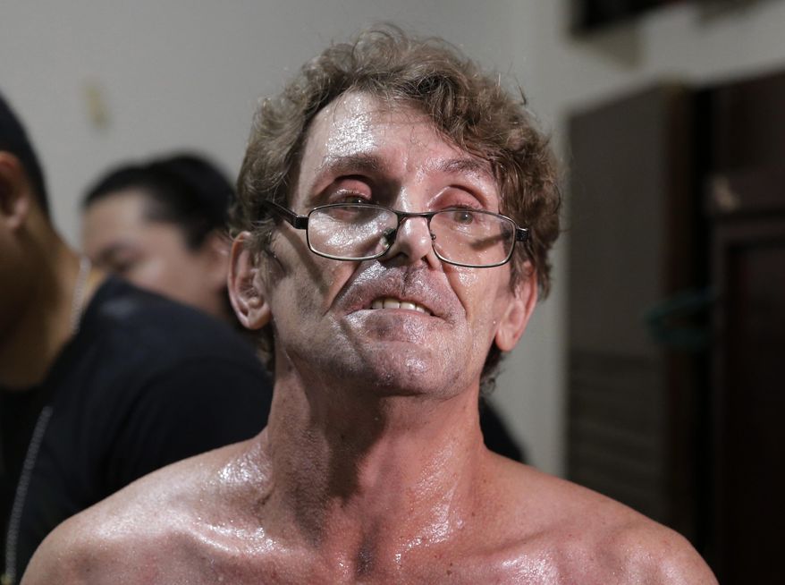 Suspected child webcam cybersex operator, American David Timothy Deakin, from Peoria, Ill., waits following his arrest as investigators gather evidence during a raid at his home in Mabalacat, northern Philippines, April 20, 2017. A Philippine court has convicted Deakin who exploited Filipino children sexually using webcams to sell videos, images and livestreams to pedophile buyers abroad, an official said Wednesday, May 27, 2020. (AP Photo/Aaron Favila)