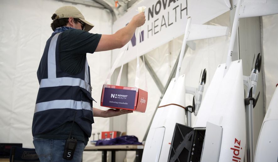 In this undated image provided by Novant Health, a package is prepared to be placed inside a drone for delivery from Novant Health Logistics Center in Kannapolis, N.C., to Novant Health Medical Center in Huntersville, N.C. North Carolina is a testing ground for drone programs involving medical supplies, and this week one of the first deliveries of personal protective equipment in the U.S. was dropped at a hospital by drone. The drones carry up to 4 pounds, and have a round-trip range of 100 miles. (Davis Turner/Novant Health via AP)