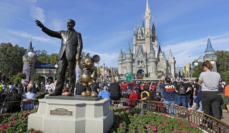 FILE - In this Jan. 9, 2019 photo, guests watch a show near a statue of Walt Disney and Micky Mouse in front of the Cinderella Castle at the Magic Kingdom at Walt Disney World in Lake Buena Vista, part of the Orlando area in Fla. Officials from SeaWorld and Disney World say they hope to open their theme parks in Orlando, Fla., in June and July. A city task force approved the plans on Wednesday, May 27, 2020. (AP Photo/John Raoux, File)