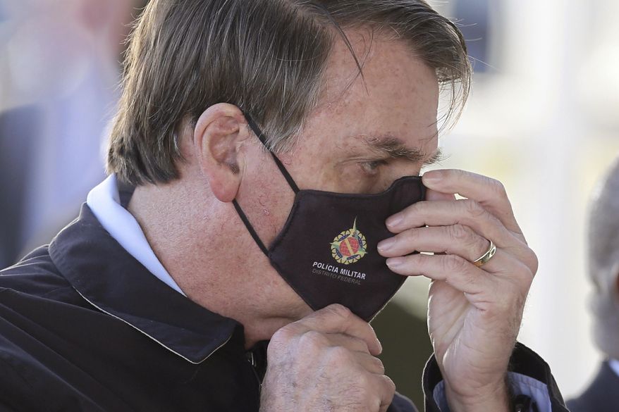 Brazil&#39;s President Jair Bolsonaro adjusts his face mask as he speaks to supporters while departing his official residence, Alvorada Palace, in Brasilia, Brazil, Thursday, May 21, 2020. (AP Photo/Eraldo Peres) ** FILE **