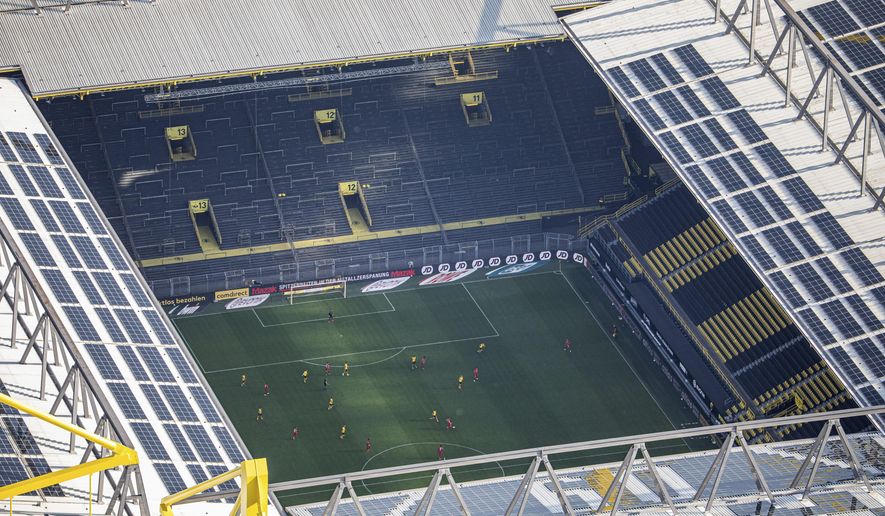 In this aerial image soccer players of both teams play the game in front of empty spectator stands during the German Bundesliga soccer match between Borussia Dortmund and FC Bayern Munich in Dortmund, Germany, Tuesday, May 26, 2020. The German Bundesliga is the world&#39;s first major soccer league to resume after a two-month suspension because of the coronavirus pandemic. (Marcel Kusch/DPA via AP, Pool)