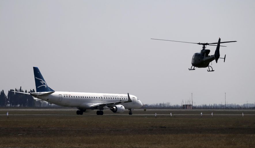 In this photo taken on Wednesday, March 15, 2017, a Montenegrin army helicopter flies near Montenegro Airlines Embraer E195LR sits on the tarmac at the Golubovci airport, near Podgorica, Montenegro.  Serbia&#39;s authorities Wednesday May 27, 2020, have banned Montenegro&#39;s national carrier from operating flights from Belgrade after the small Adriatic state excluded Serbian citizens from a list of countries with which it will reopen its borders after declaring an end to the coronavirus epidemic. (AP Photo/Darko Vojinovic)