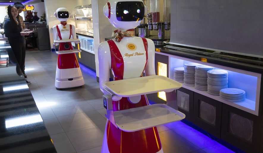 Leah Hu, left, and her brother Leon demonstrate the use of robots for serving purposes or for dirty dishes collection, as part of a tryout of measures to respect social distancing and help curb the spread of the COVID-19 coronavirus, at the family&#39;s Royal Palace restaurant in Renesse, south-western Netherlands, Wednesday, May 27, 2020. (AP Photo/Peter Dejong)