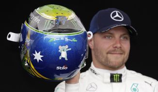Mercedes driver Valtteri Bottas of Finland shows his helmet with a koala painted on it as he poses for a photo at the Australian Formula One Grand Prix in Melbourne, Thursday, March 12, 2020. (AP Photo/Rick Rycroft)
