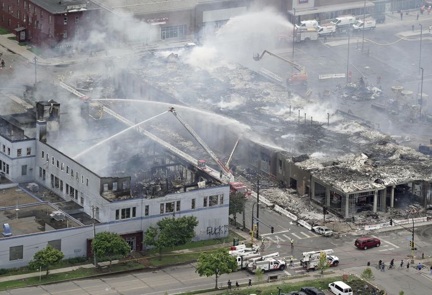 Firefighters work on an apartment building under construction, Thursday, May 28, 2020, tentatively known as Midtown Corner, left, after it was burned to the ground in Minneapolis, Minn. during protests. Minneapolis residents awoke Thursday to assess the damage after rioters ignited fires and looted stores all over the city, as peaceful protests turned increasingly violent in the aftermath the death of George Floyd during an arrest. (Brian Peterson/Star Tribune via AP)