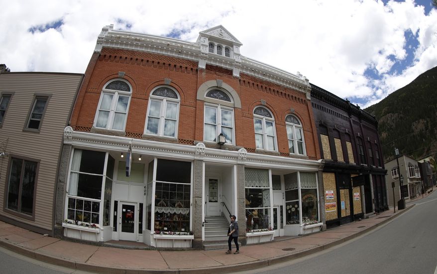 As viewed through a fisheye lens, a lone pedestrian walks along Sixth Street pat shuttered shops closed to help in the effort to stop the spread of the new coronavirus, Wednesday, May 27, 2020, in Georgetown, Colo. (AP Photo/David Zalubowski)