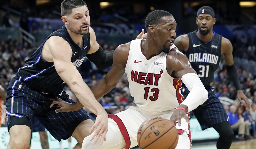 FILE - In this Feb. 1, 2020, file photo, Miami Heat forward Bam Adebayo (13) tries to get around Orlando Magic center Nikola Vucevic, left, and guard Terrence Ross (31) during the first half of an NBA basketball game in Orlando, Fla. Reporters from The Associated Press spoke to more than two dozen athletes from around the globe -- representing seven countries and 11 sports -- to get a sense of how concerned or confident they are about resuming competition. What emerged, above all, was a sense that they are going through the very same sort of calculus that much of the rest of society is: What is safe nowadays? (AP Photo/John Raoux, File)