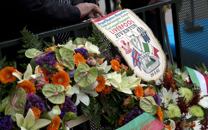 FILE - In this Friday, May 29, 2015 file photo, a man holds an original banner from the 1985 match during a commemoration at the King Boudouin (formerly the Heysel) Stadium in Brussels. Friday, May 29, 2020 marks 35 years since 39 victims lost their lives during a European Cup football match between Liverpool and Juventus due to a surge of rival supporters resulting in a collapsed wall. (AP Photo/Virginia Mayo, File)