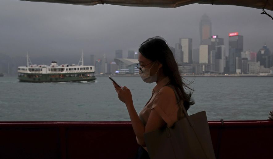 In this Thursday, May 28, 2020, photo, a woman uses a smartphone on a ferry in Hong Kong. Hong Kong has been living on borrowed time ever since the British made it a colony nearly 180 years ago, and all the more so after Beijing took control in 1997, granting it autonomous status. A national security law approved by China&#39;s legislature Thursday is a reminder that the city&#39;s special status is in the hands of Communist Party leaders who have spent decades building their own trade and financial centers to take Hong Kong&#39;s place. (AP Photo/Kin Cheung)