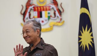 FILE - In this April 15, 2019, file photo, Malaysian Prime Minister Mahathir Mohamad waves good bye to media after a press conference in Putrajaya, Malaysia. Former Prime Minister Mahathir has been ousted from his Malay party in the latest twist to a power struggle with his successor Muhyiddin Yassin, but he has vowed to challenge the move. The 94-year-old Mahathir, along with his son and three other senior members, were expelled from the Bersatu party on Thursday, May 28, 2020. (AP Photo/Vincent Thian, File)