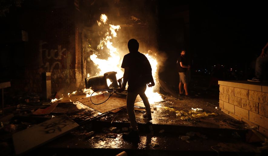 EDS NOTE: OBSCENITY - Protesters add fuel to a fire at the Minneapolis police 3rd Precinct building Thursday, May 28, 2020, in Minneapolis. Violent protests over the death of George Floyd, a black man who died in police custody Monday, broke out in Minneapolis for a third straight night. (AP Photo/John Minchillo)
