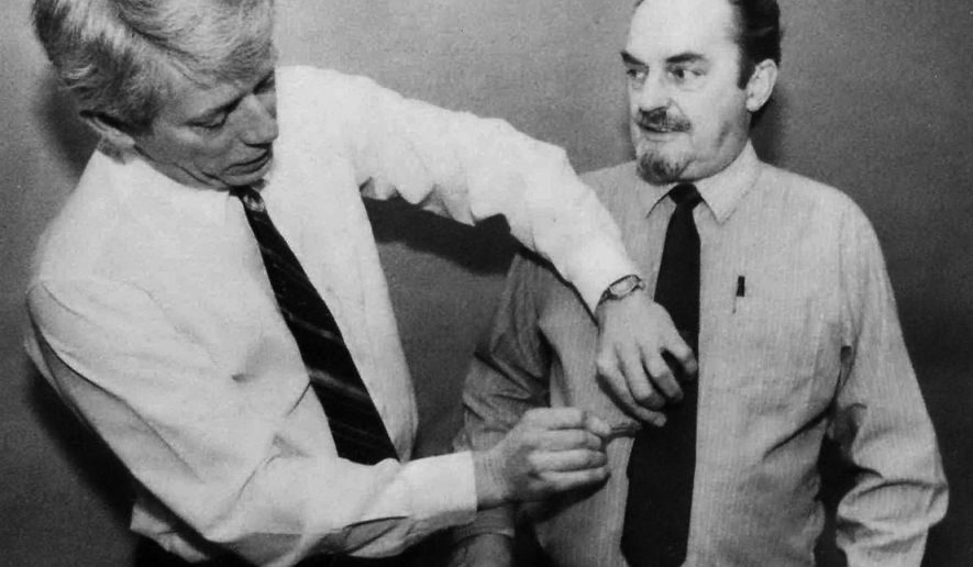 FILE - In this 1988 file photo, Associated Press overnight supervisor at the time, Al Orton Jr., right, has an AP tie tack pinned to his tie by Columbus Chief of Bureau Jake Booher on Orton's 25th anniversary with the wire service in Columbus, Ohio. Orton, a veteran Associated Press journalist who spent much of his career on the overnight shift, mentoring dozens of reporters along the way, died Wednesday, May 27, 2020, in Columbus, of a heart attack after experiencing several health problems, said his son, Andrew Orton. He was 84. (AP Photo/Gary Gardiner, File)