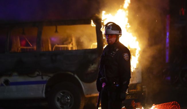 A police officer walks past a burning police vehicle on DeKalb Avenue in the Brooklyn borough of New York, Friday, May 29, 2020, after protesters gathered at Barclays Center to express anger over the death of George Floyd, a black man who died Memorial Day while in police custody in Minneapolis. (AP Photo/Frank Franklin II) **FILE**
