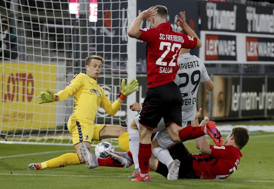 Leverkusen's Kai Havertz, center right, scores the opening goal during the German Bundesliga soccer match between SC Freiburg and Bayer 04 Leverkusen in Freiburg, Germany, Friday, May 29, 2020. Because of the coronavirus outbreak all soccer matches of the German Bundesliga take place without spectators. (Ronald Wittek/Pool via AP)