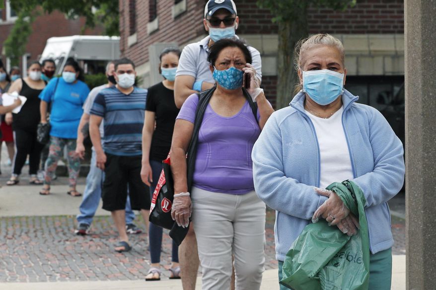Residents wearing protective masks, due to the coronavirus outbreak, wait in line for boxes of donated food for those in need in Chelsea, Mass., Friday, May 29, 2020. (AP Photo/Charles Krupa)