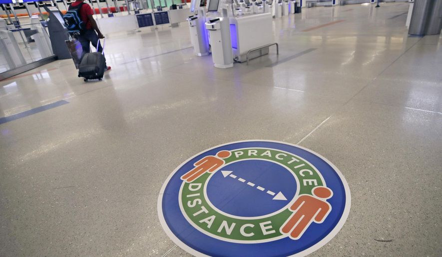 A traveler passes a sign recommending practicing social distancing, to limit spread of the coronavirus outbreak, at the nearly passenger-less JetBlue terminal at Logan Airport in Boston, Friday, May 29, 2020. (AP Photo/Charles Krupa)