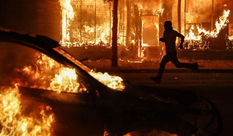 A protester runs past burning cars and buildings on Chicago Avenue, Saturday, May 30, 2020, in St. Paul, Minn. Protests continued following the death of George Floyd, who died after being restrained by Minneapolis police officers on Memorial Day. (AP Photo/John Minchillo)