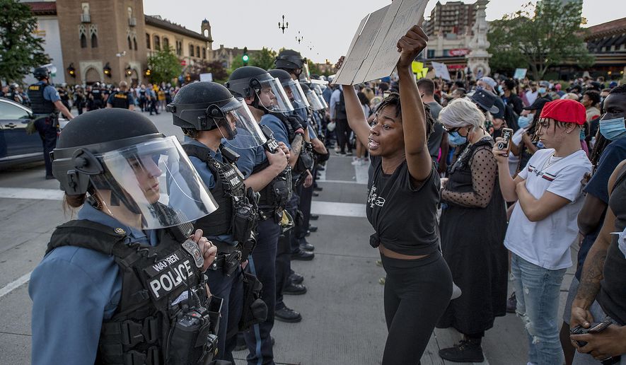 In this May 29, 2020, photo, a woman holds a placard as she screams "You have no authority to kill minorities," at Kansas City Police during a protest against police brutality and the death George Floyd at the Country Club Plaza in Kansas City. Protests have been erupting all over the country after George Floyd died earlier this week in police custody in Minneapolis. (Tammy Ljungblad/The Kansas City Star via AP)
