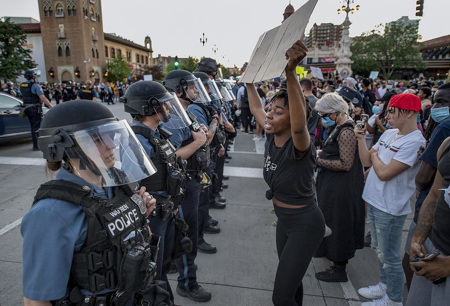 In this May 29, 2020, photo, a woman holds a placard as she screams "You have no authority to kill minorities," at Kansas City Police during a protest against police brutality and the death George Floyd at the Country Club Plaza in Kansas City. Protests have been erupting all over the country after George Floyd died earlier this week in police custody in Minneapolis. (Tammy Ljungblad/The Kansas City Star via AP)