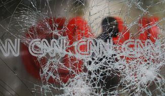 A security guard walks behind shattered glass at the CNN building at the CNN Center in the aftermath of a demonstration against police violence on Saturday, May 30, 2020, in Atlanta. (AP Photo/Brynn Anderson)
