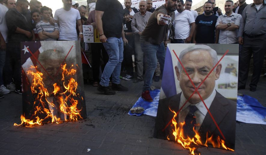 Palestinians burn pictures of U.S. President Donald Trump, left, and Israeli Prime Minister Benjamin Netanyahu during a protest against Trump's mideast initiative, in the West Bank city of Nablus, Saturday, May 30, 2020.(AP Photo/Majdi Mohammed)