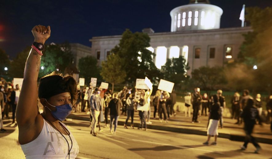 A woman raises her fist in defiance near the Ohio Statehouse as several hundred people gather to protest over the death of George Floyd Friday, May 29, 2020, ion Columbus, Ohio. Floyd died in police custody Monday in Minneapolis. (Doral Chenoweth/The Columbus Dispatch via AP) **FILE**