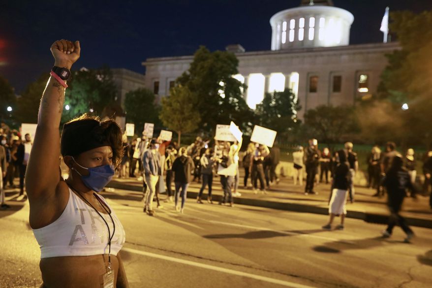 A woman raises her fist in defiance near the Ohio Statehouse as several hundred people gather to protest over the death of George Floyd Friday, May 29, 2020, ion Columbus, Ohio. Floyd died in police custody Monday in Minneapolis. (Doral Chenoweth/The Columbus Dispatch via AP) **FILE**