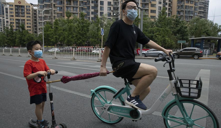 A man pulls a child along as they wear masks to curb the spread of the new coronavirus on the streets of Beijing, Saturday, May 30, 2020. (AP Photo/Ng Han Guan)