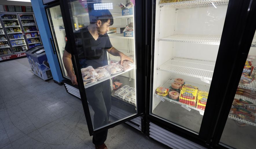 Hardik Kalra stocks meat in a cooler at a local super market, Friday, May 29, 2020, in Des Moines, Iowa. As if trips to the grocery store weren't nerve-racking enough, shoppers lately have seen the costs of meat, eggs and even potatoes soar as the coronavirus has disrupted processing plants and distribution networks. (AP Photo/Charlie Neibergall)
