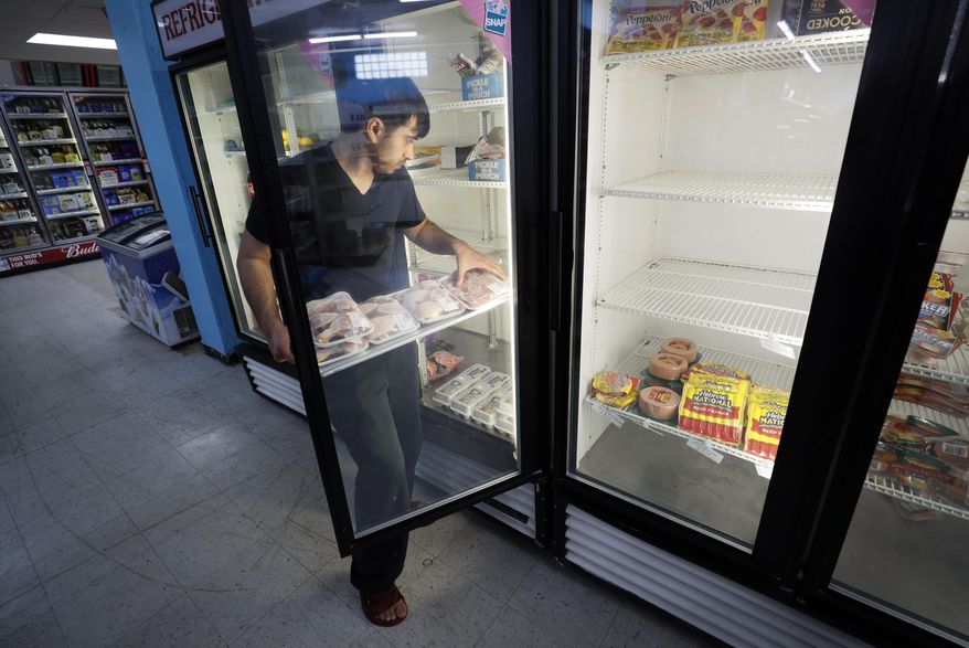 Hardik Kalra stocks meat in a cooler at a local super market, Friday, May 29, 2020, in Des Moines, Iowa. As if trips to the grocery store weren't nerve-racking enough, shoppers lately have seen the costs of meat, eggs and even potatoes soar as the coronavirus has disrupted processing plants and distribution networks. (AP Photo/Charlie Neibergall)