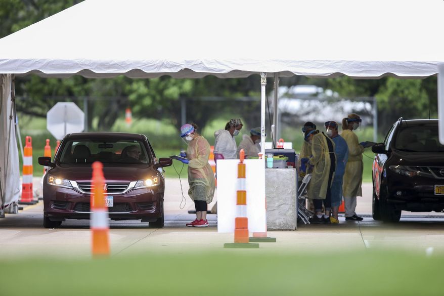 Medical workers perform coronavirus testing on people in vehicles at a Test Iowa site at the Kirkwood Community College Continuing Education Training Center in Cedar Rapids, Iowa, Thursday, May 28, 2020. Those wishing to be tested are required to have an appointment and show a QR code in order to enter. (Rebecca F. Miller/The Gazette via AP)